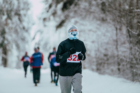 closeup young male runner participant of winter marathon. face frost, cold weather