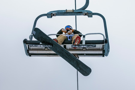 young athlete rises snowboarder on ski lift to startの写真素材