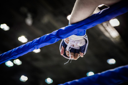 hand of fighter on ropes of ring during competition in mixed martial artsの写真素材