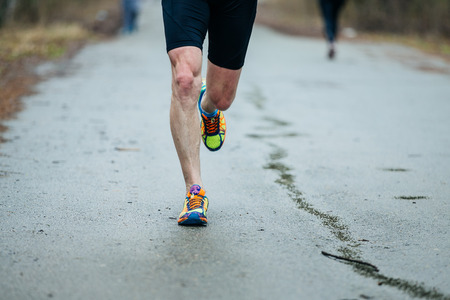 closeup feet of young runner men running along road in Park during marathon. front viewの写真素材