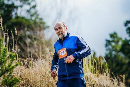 Ekaterinburg, Russia -  April 24, 2016: elderly man athlete running on hill during a Mountain marathonのeditorial素材