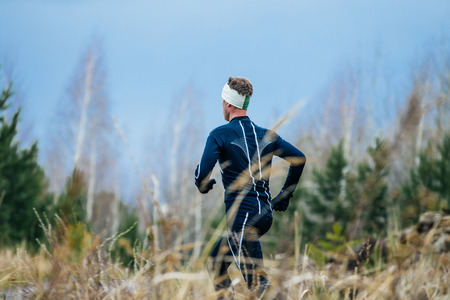 young male athlete running down hill amongst dry grass