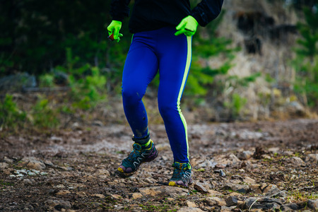 legs girl athlete running on mountain trail of stones during marathonの写真素材