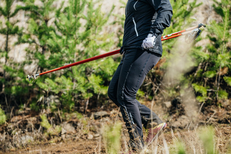 male runner with walking sticks down from mountain in forestの写真素材