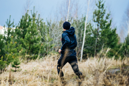 view from back of a young male marathon runner running down hill amongst dry grassの写真素材