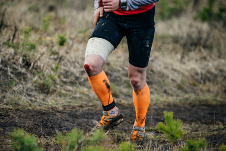 legs male athlete running on forest trail. feet in mud, knee-deep in bloodの写真素材
