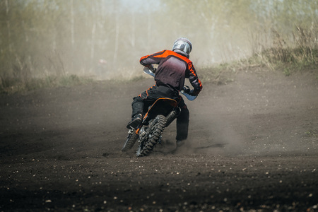 racer motorcycle rides on dusty track during competition racingの写真素材