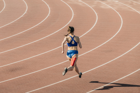 girl sprinter runs through stadium. feet tapingの写真素材