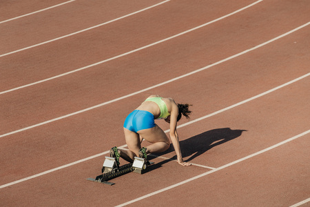 female athlete preparing for start of sprint at stadiumの写真素材