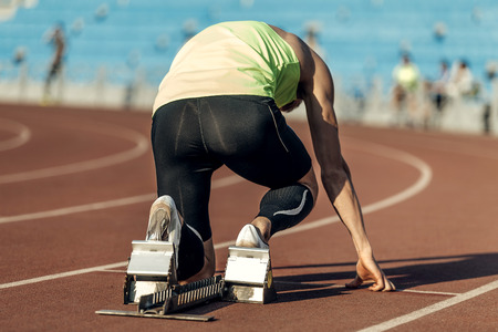 male athlete in starting blocks. running at sprint at stadiumの写真素材