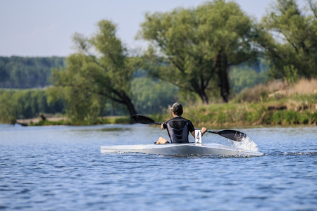 young athlete on rowing kayak on lake during competition
