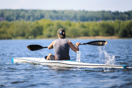 athlete rower on rowing kayak on lake during competition. splashes of water under paddleの写真素材