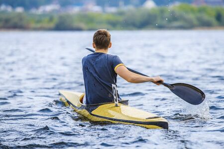 young man in a canoe rowing oars. boating in  lakeの写真素材