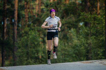 Miass, Russia - June 26, 2016: female athlete running on road in forest during Marathon "Clean water"のeditorial素材