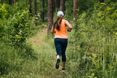 girl running on forest trail in summer during marathonの写真素材