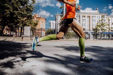 legs of a young male athlete in compression socks running marathonの写真素材
