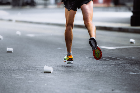 male athlete running on asphalt of empty cups from waterの写真素材