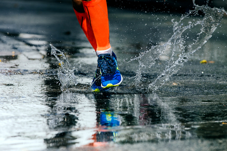 legs men in marathon compression socks, running through a puddle, water spraysの写真素材