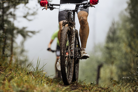closeup wheel mountainbike and feet rider in spray of dirt. riding in autumn forestの写真素材