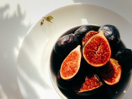 chopped figs lies on a white plate in sun rayの写真素材