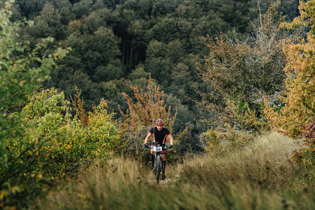 male rider cyclist riding uphill among woods and grass during Crimean race mountainbikeのeditorial素材