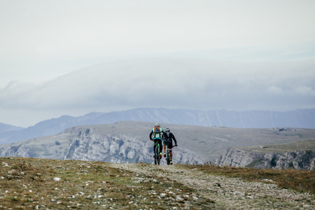 two cyclist on sports bikes riding on a mountain road. on background of mountains and skyの写真素材