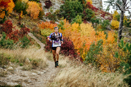 runner skyrunner runs with walking sticks on a mountain trail in autumn forest during Crimea mountain marathonのeditorial素材