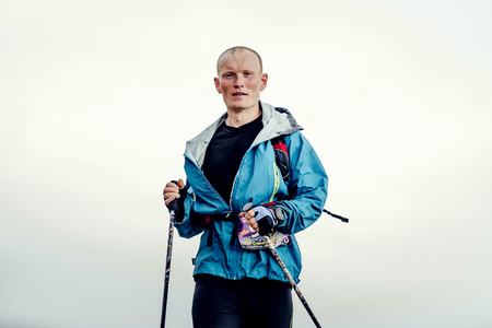 closeup of runner skyrunner with walking sticks running on background blue sky during Crimea mountain marathonのeditorial素材