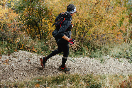 sports middle-aged man traveling on a mountain trail in autumn forest