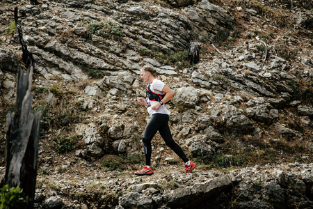 young runner runs on a mountain trail in background stone rocks during Crimea mountain marathonのeditorial素材