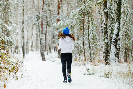 redheads girl runner runs at winter Park in falling snowの写真素材