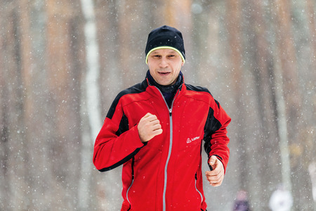 Ekaterinburg, Russia - November 26, 2016: closeup male runner running in falling snow in forest during Winter marathonのeditorial素材