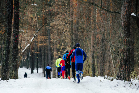 back a group of male runners running winter woods marathonの写真素材