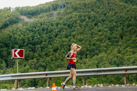 Rosa Khutor, Russia -  May 7, 2017: young woman runner on water point in hand sponge with water in race Spring mountain marathonのeditorial素材