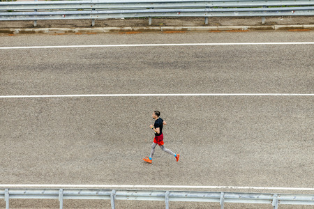 Rosa Khutor, Russia -  May 7, 2017: side view of male runner running on dark asphalt road in race Spring mountain marathonのeditorial素材
