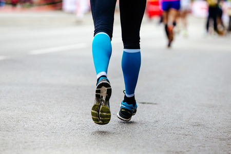back feet woman runner in blue compression socks running streetの写真素材