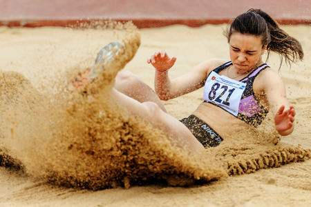 Chelyabinsk, Russia - June 4, 2017: woman athlete landing in sand long jump during UrFO Championship...