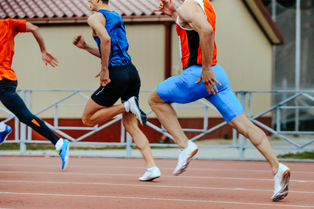 three runners sprinters men run in stadium on competitionの写真素材