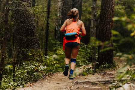 woman runner in knee pad running trail forestの写真素材
