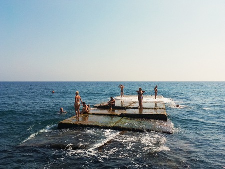 Yalta, Crimea - September 20, 2017: group of people swimming and sunbathing on breakwaterのeditorial素材