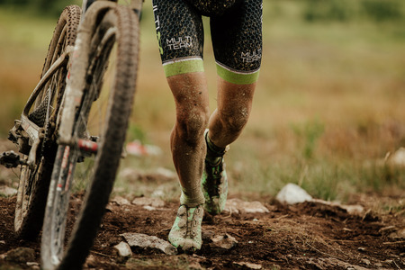 V.Ufaley, Russia - August 12, 2018: dirty bike and legs mountain biker uphill walk during race XCM Big stoneのeditorial素材