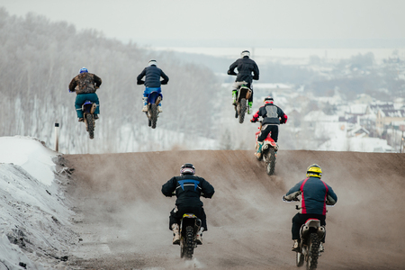group riders enduro motorbike jump over hill in trackの写真素材