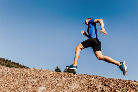 athlete runner run uphill trail on blue sky background