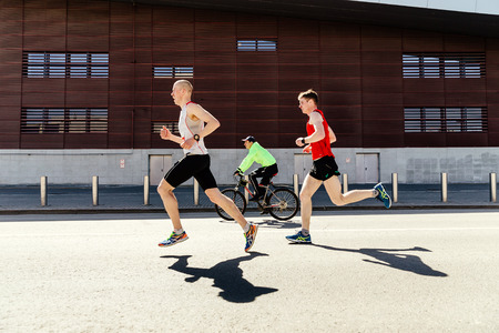 Ekaterinburg, Russia - May 2, 2019: two man runners athletes running street in May storm Runのeditorial素材