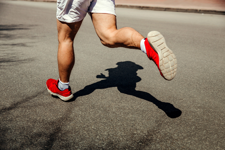 feet man runner running street. shadow runner on gray asphaltの写真素材