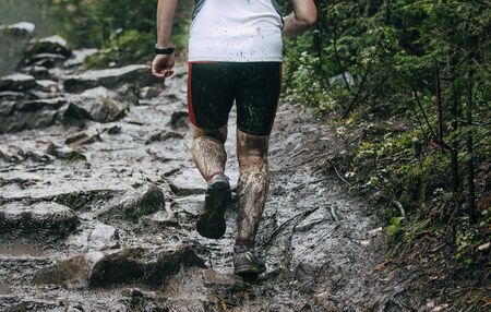 back man runner run autumn mountain trail through mud and waterの写真素材