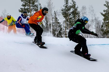 snowboard cross competition group of athletes downhill on snowy track