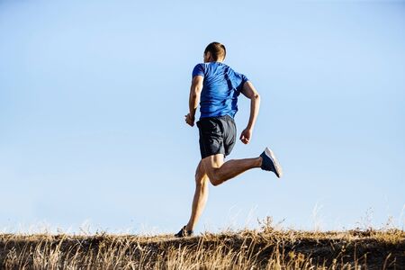 back male runner run in blue shirt and shorts on mountain trail