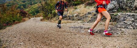 woman and man runners run mountain trail in autumn cloudy weatherの写真素材