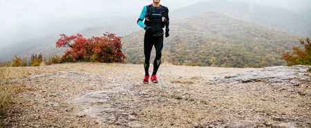 male runner run mountain trail. rain and fog, autumn weather